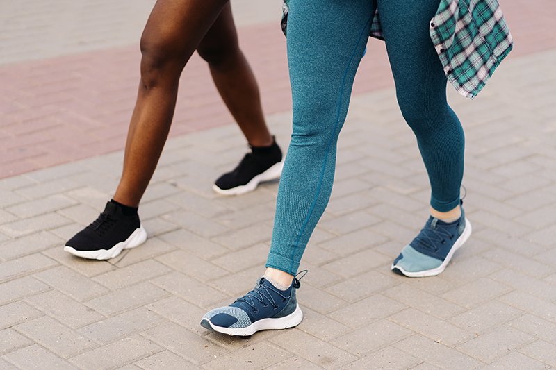 Two multiethnic girls legs jogging through the city streets, outdoor communicating. 10,000 Steps a Day: Health Benefits of Daily Walking